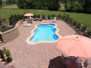 freeform pool and concrete paver patio with oversized umbrellas and lounge chairs