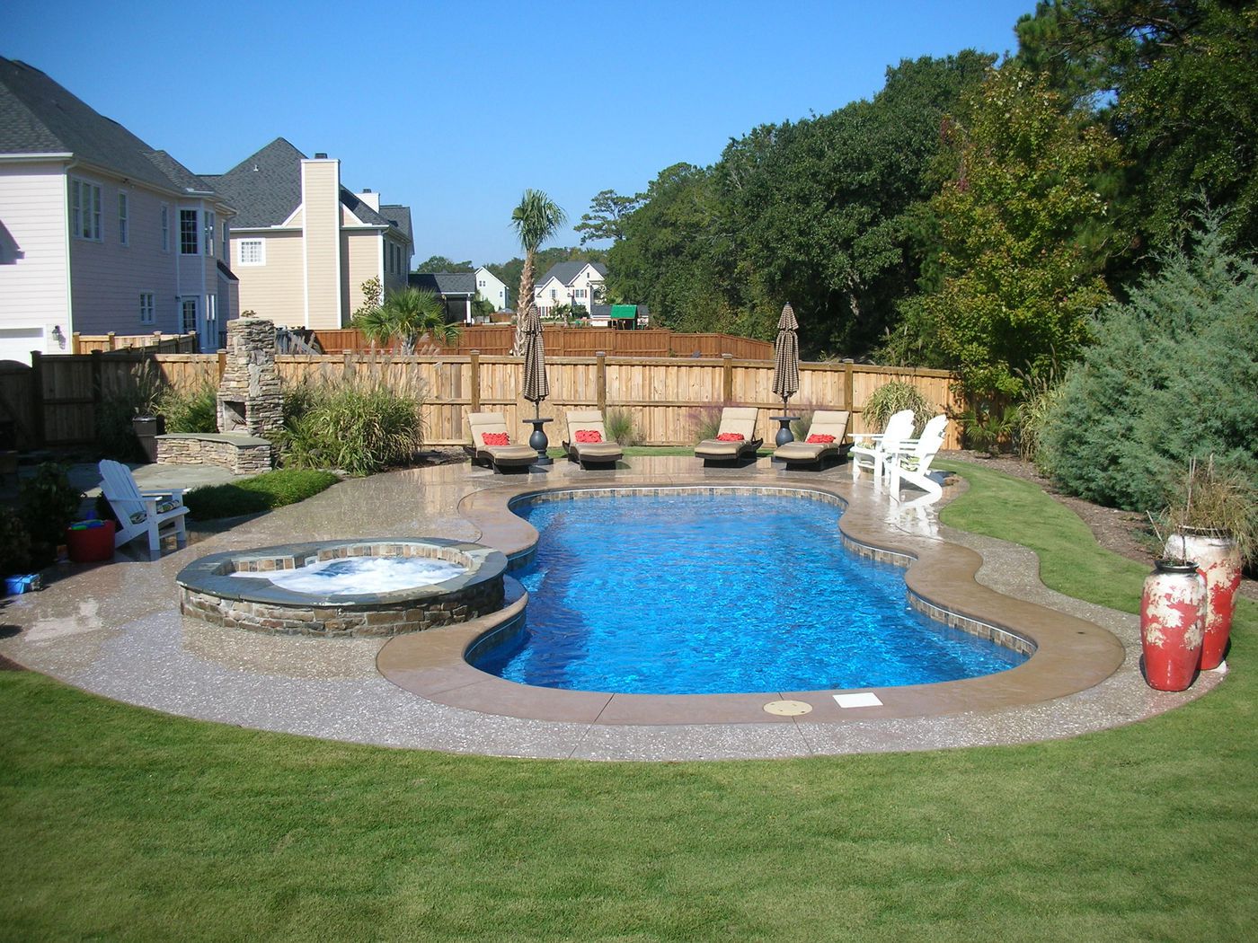 fiberglass swimming pool with deck and landscaping