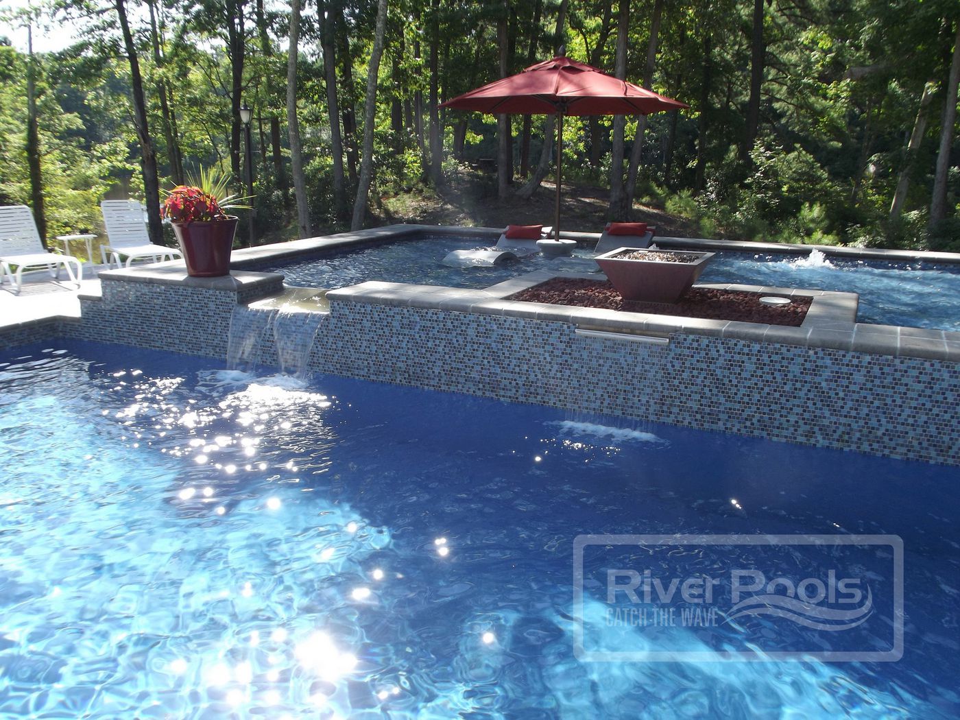 Fiberglass swimming pool with water feature and raised tanning ledge
